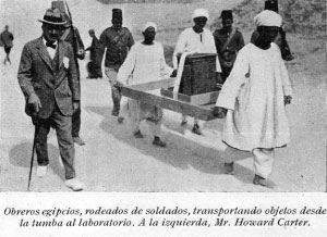 Obreros egipcios, rodeados de soldados, transportando objetos desde la tumba al laboratorio. A la izquierda, Mr Howard Carter.