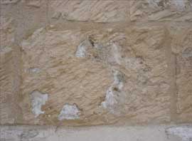 Eflorescencias de sales por debajo del mortero de restauracin, que provoca su desprendimiento y el deterioro de la piedra.